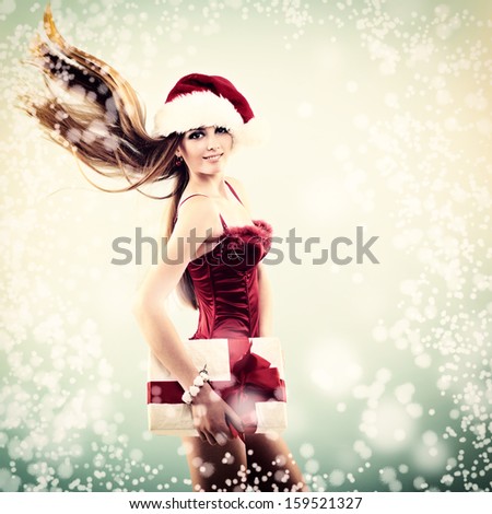 Beautiful cheerful fashion christmas girl in Santa\'s hat with gift box in snow, toned