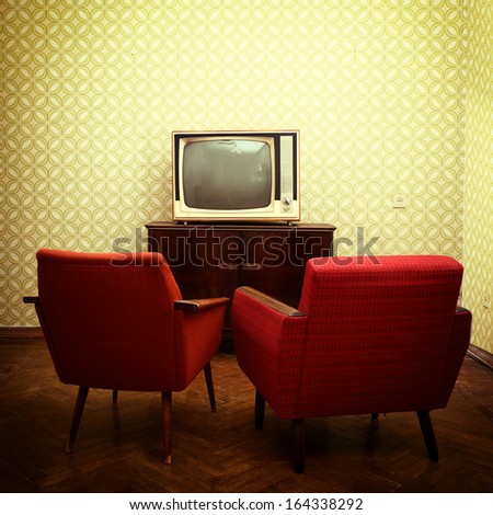 Vintage room with two old fashioned armchairs and retro tv over obsolete wallpaper. Toned