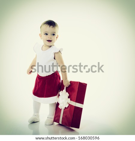 Holidays, baby girl holding a present, christmas, birthday, new year, x-mas concept - happy child girl with gift boxes