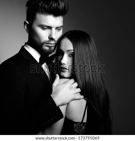 Portrait of beautiful young man and woman dressed in classic clothes, studio shot over grey background. Sexy passion couple in love.