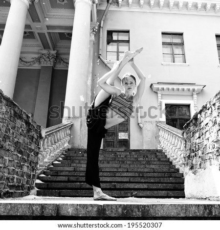 Attractive teen girl dancing outdoor in park against old building with columns. Black and white.