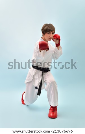fighting karate girl, young woman with black belts - champions of the world, over blue background studio shot