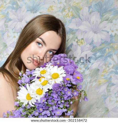 Young beautiful woman holding bunch of wild flowers. Attractive girl looking at camera Health care, skin care, beauty treatment, cosmetology, youth and aging concept.