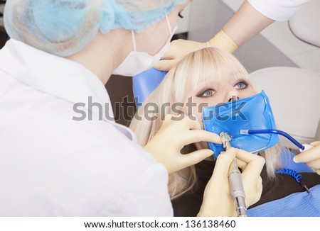 modern dental equipment. dentist treats tooth decay in the teeth with a dental drill, saliva ejector, the rubber dam. Young blond girl in the dentist\'s chair