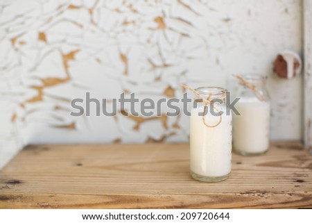 Two milk products bottle standing on a wooden table on a background of old furniture. Still-life with natural healthful food. Dairy