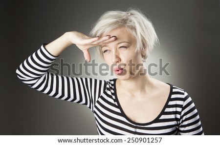 Blonde in a vest looks into the distance put her hand to her forehead