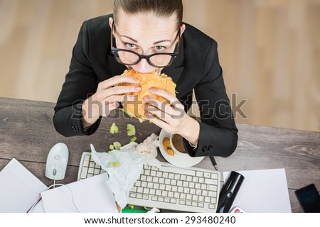 Overhead View Of Businesswoman eating At Computer In Office at work place. The modern pace of life there is no time for healthy eating