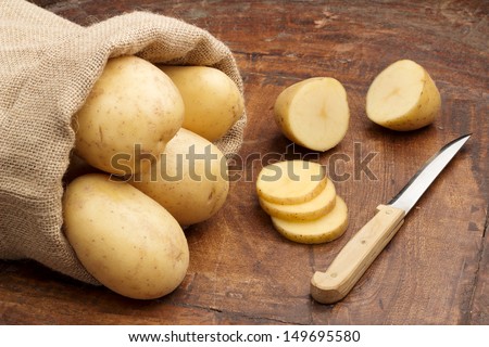 raw potatoes and knife on a wooden background