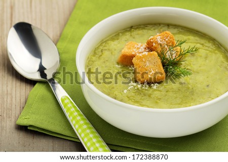 vegetable soup, green napkin and tablespoon on wooden board