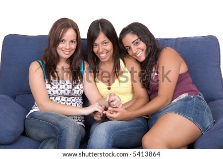 Three young smiling women are sitting on a blue couch. They are very happy and holding their hands together - Friendship  - over a white background
