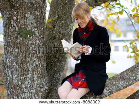 Young student girl is studying outside near the tree 1