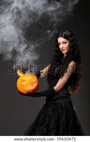 Halloween witch with a broom and smoke coming out of carved pumpkin
