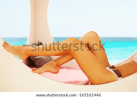 Closeup of female legs in the beach booth on a summer day