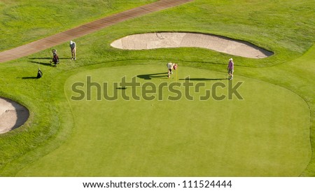 A high angle view of a group of golfers on a putting green.