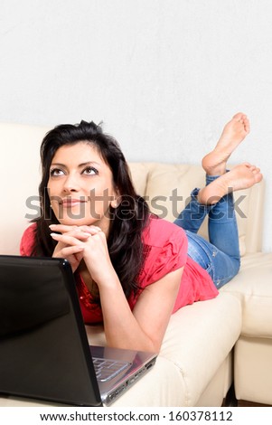 Beautiful Caucasian woman smiles thinking in front of his laptop. Concept of the Internet.