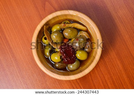 Bowl filled with freshly harvested whole fresh green olives on a wooden tabletop.