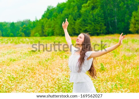 brunette with a flower field with arms outstretched to the sides