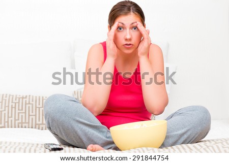 frightened woman looking on TV a horror movie