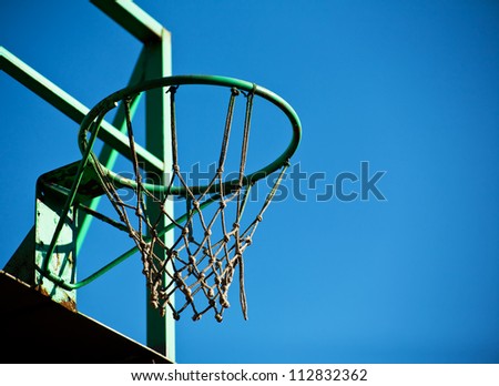 Old basketball basket with a blue sky in the background.
