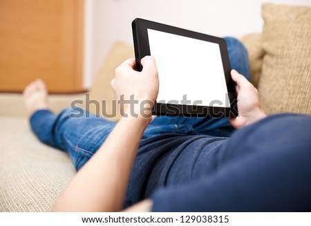 Man relaxing with tablet, laying on sofa
