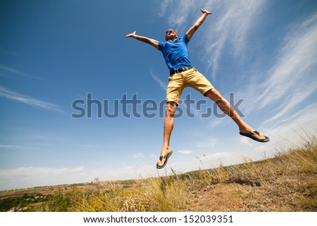 Happy man jumping, blue sky on background, wide angle