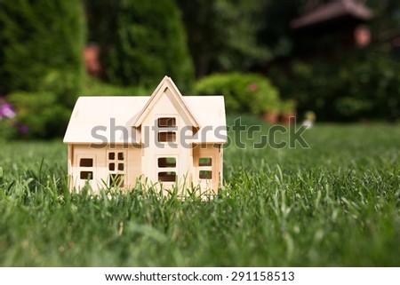 Wooden model of house on grass,  summer outdoor, new home concept
