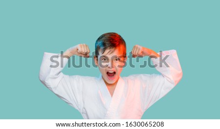 Karate young boy in white uniform makes a hit aggressively shouting o n blue background Stock fotó © 