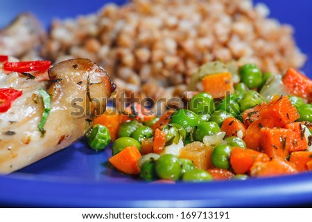 Oven baked rabbit legs with green peas and carrot
