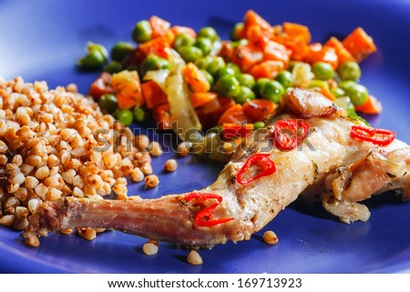 Oven baked rabbit legs with green peas and carrot