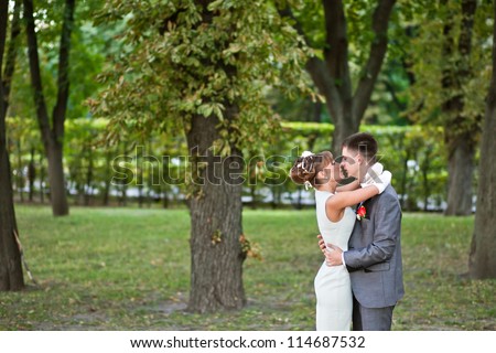 Wedding: young couple standing in a park in the open grief and hugging each other