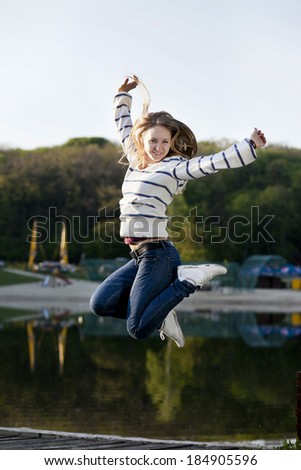 Young girl jumped up on a background of lake