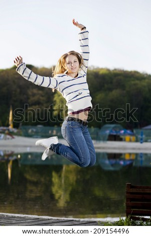 Young girl jumped up on a background of lake
