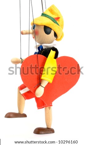 Wooden doll - marionette. Joyfully it steps with the enormous red heart. Side view. Valentine\'s Day.