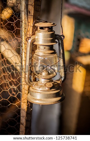 An old rusty oil lamp hanging on a wood fence