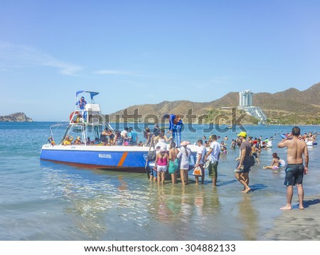 SANTA MARTA, COLOMBIA, JANUARY - 2015 - People aboarding a boat trip to caribbean island from beach at El Rodadero, one of the most famous and visited watering places of Colombia.