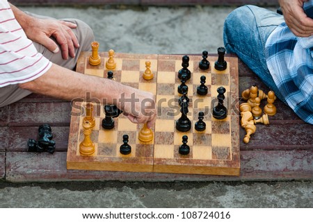 two old men play old chess on a shabby board