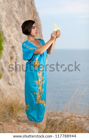 girl in blue indian dress with origami on seacoast