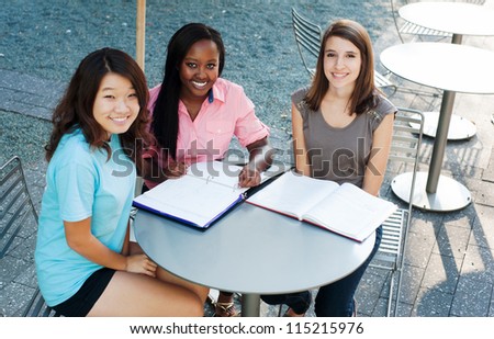 Ethnic group of girls outside studying and smiling