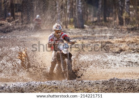 Motocross racer splashing mud on wet and muddy terrain in Finland.