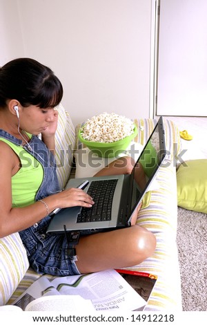 Girl of generation Y doing many things at the same time (calling,  watching tv, Surfing the web and eating popcorn)