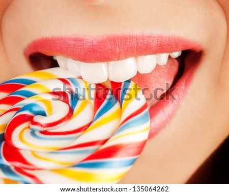 Biting candy with white healthy teeth