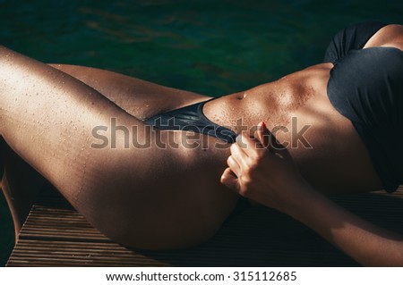 Fitness model showing her abs and body by the sea