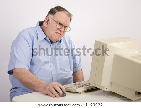 older male working on computer and grimacing