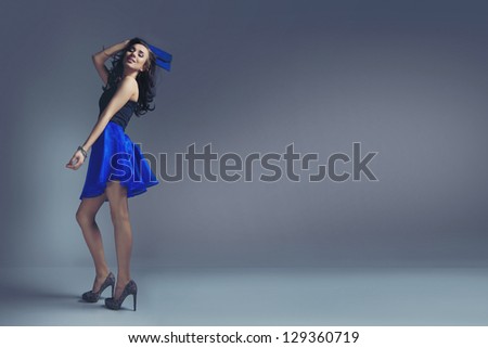 Young woman in navy blue skirt and black top on grey background