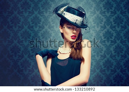 Beautiful woman in a vintage hat over a fashion background