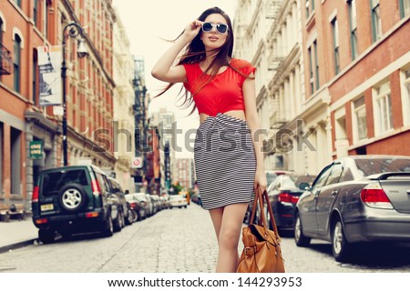 Beautiful brunette young woman wearing dress and walking on the street
