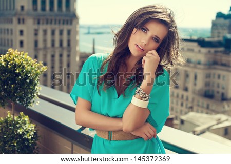 Beautiful brunette woman wearing loose dress standing on the rooftop