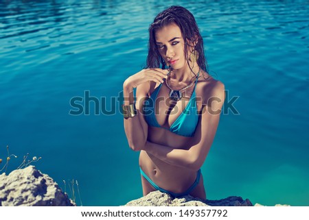Beautiful long hair female model wearing bikini, posing in the water, outdoor portrait