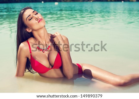 Long hair female model wearing bikini, posing in the water, outdoor portrait