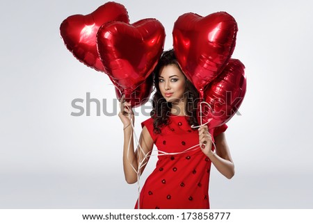 Beautiful brunette young woman in red dress with a heart-shaped balloons. Valentine\'s day